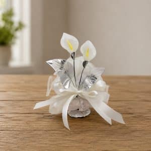 Decorative white and silver floral centerpiece with ribbons on a wooden table