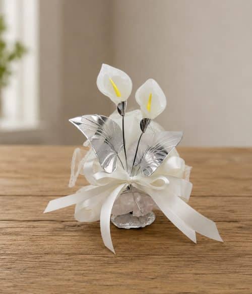 Decorative white and silver floral centerpiece with ribbons on a wooden table