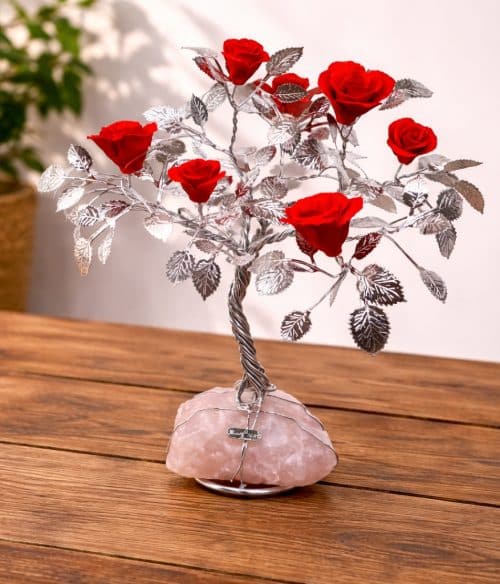 Albero decorativo con rose rosse su quarzo rosa