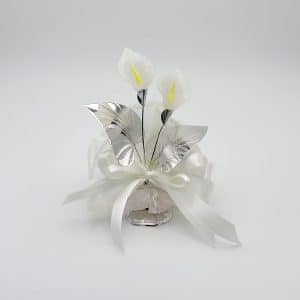 White decorative centerpiece with two artificial calla lilies, silver leaves, and a white satin bow on a glass base.