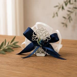Decorative silver filigree corsage with navy ribbon and blue beads on a wooden surface, ready for a wedding.