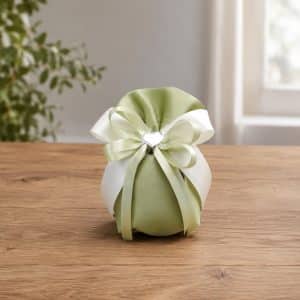 Green satin gift pouch with pale green and white ribbon bow on a wooden table surface