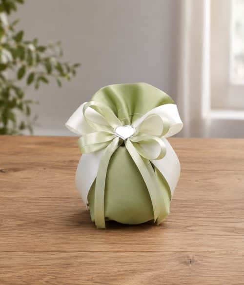Green satin gift pouch with pale green and white ribbon bow on a wooden table surface